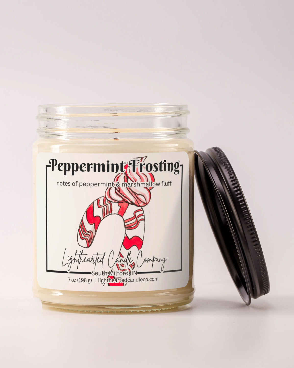 Unlit Peppermint Frosting Candle in a clear glass jar with its black lid beside it