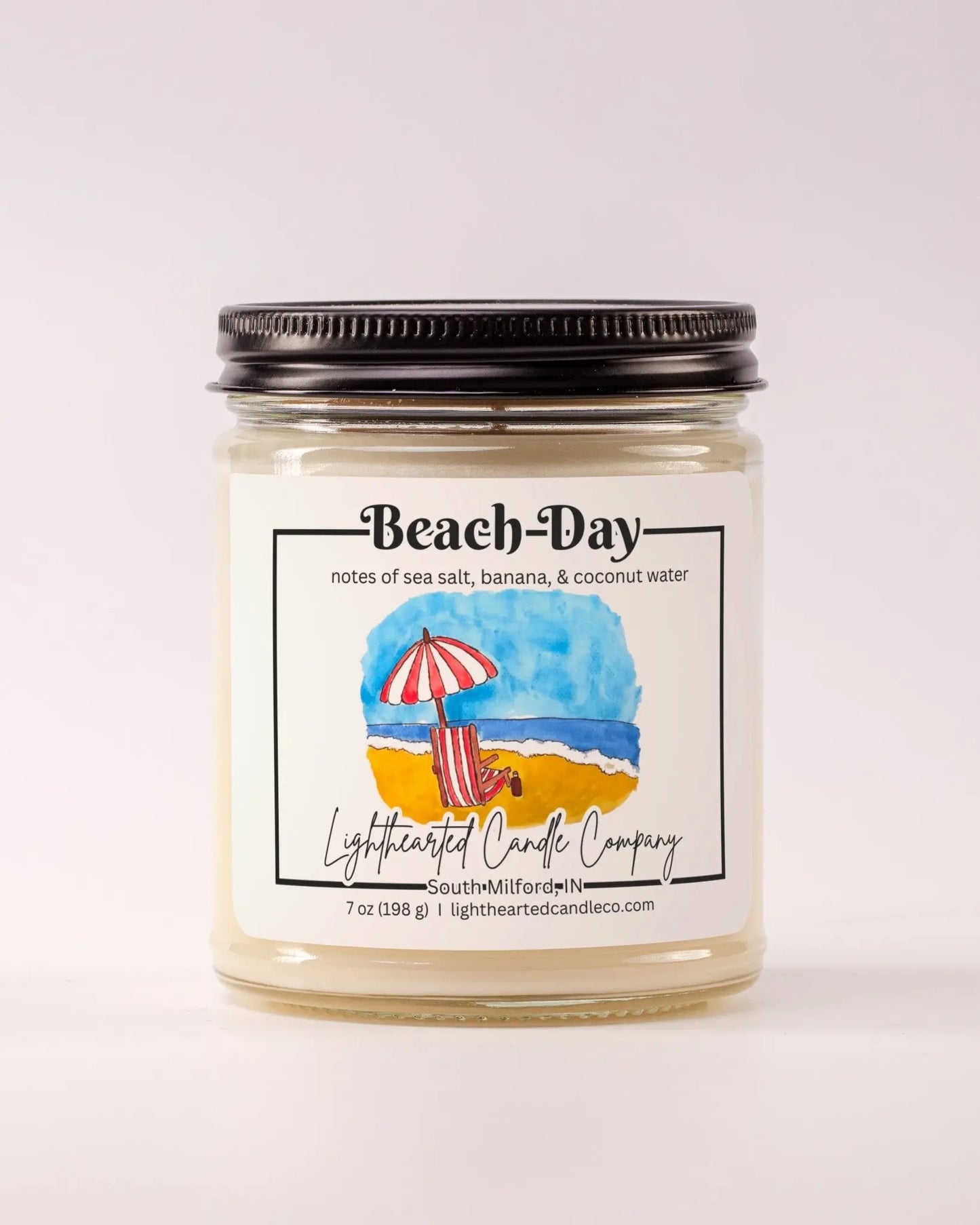 Closed Beach Day Candle in a clear glass jar with a black metal lid