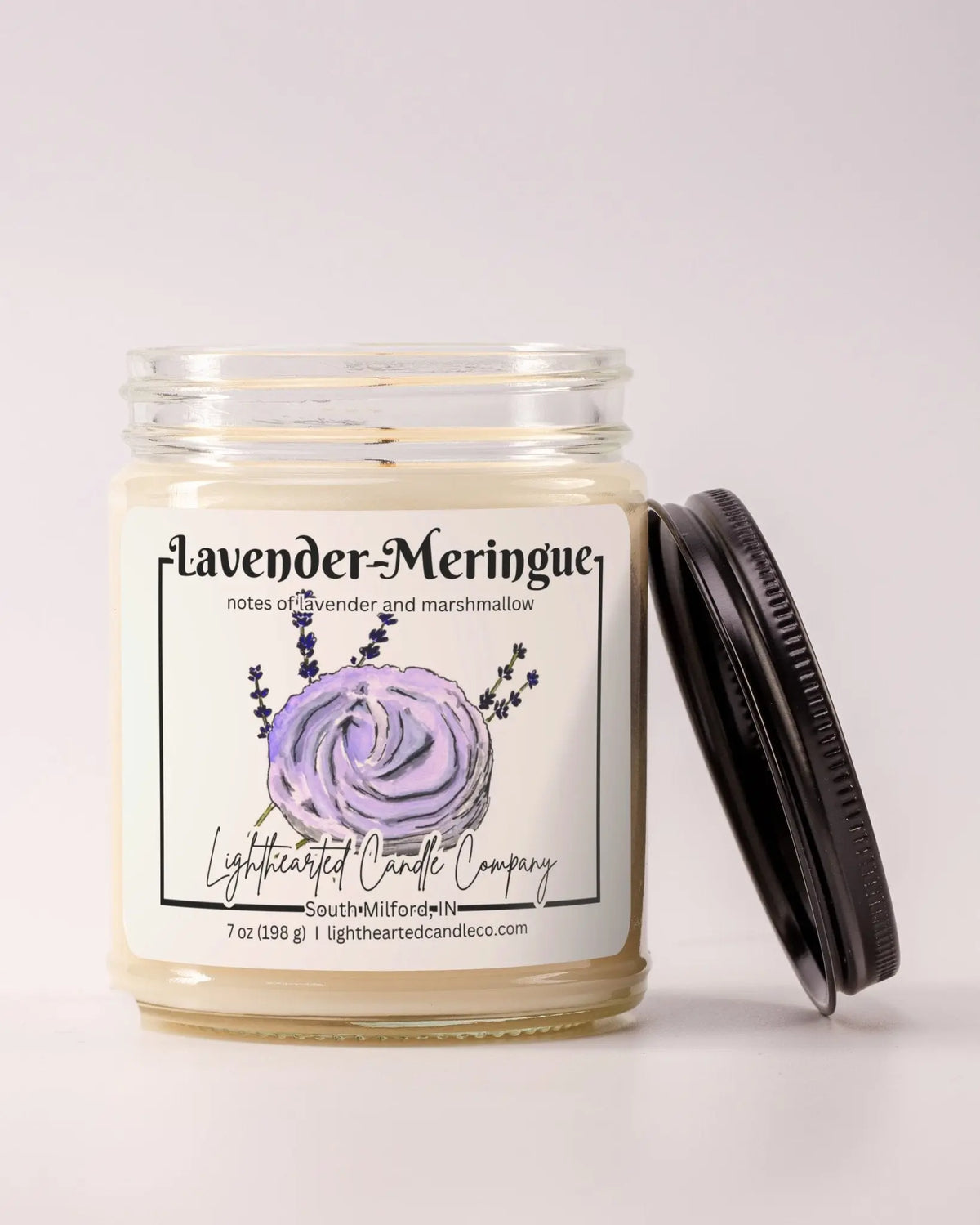 Unlit Lavender Meringue Candle in a clear glass jar with its black lid beside it