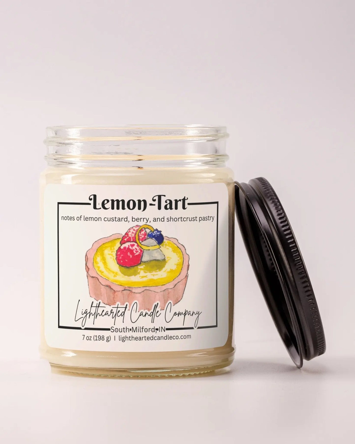 Unlit Lemon Tart Candle in a clear glass jar with its black lid beside it