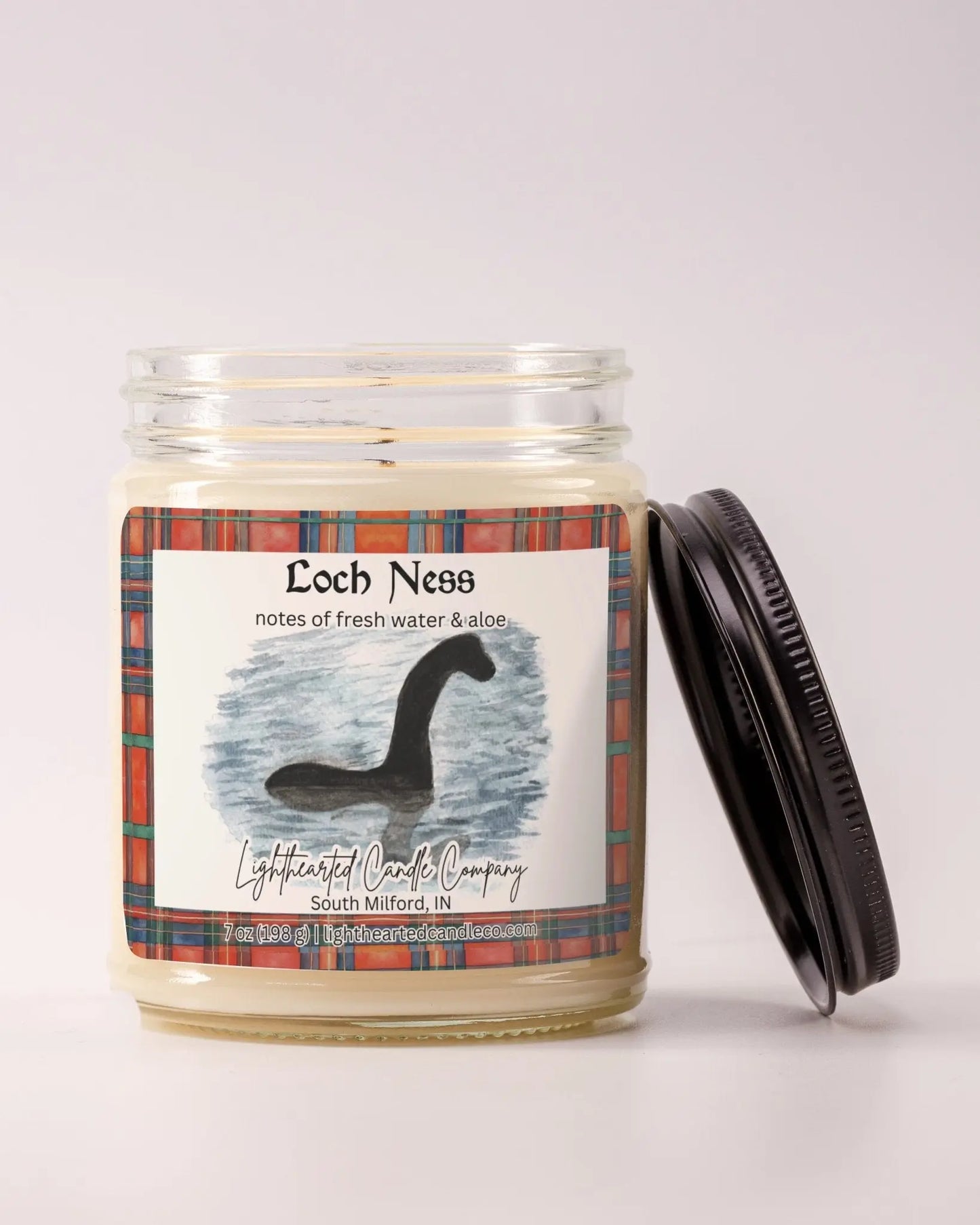 Unlit Loch Ness Candle in a clear glass jar with its black lid beside it
