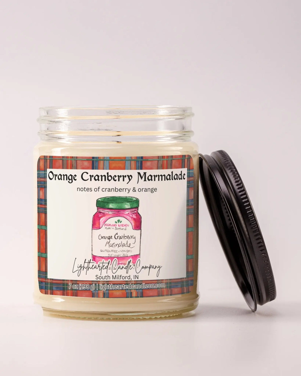 Unlit Orange Cranberry Marmalade Candle in a clear glass jar with its black lid beside it