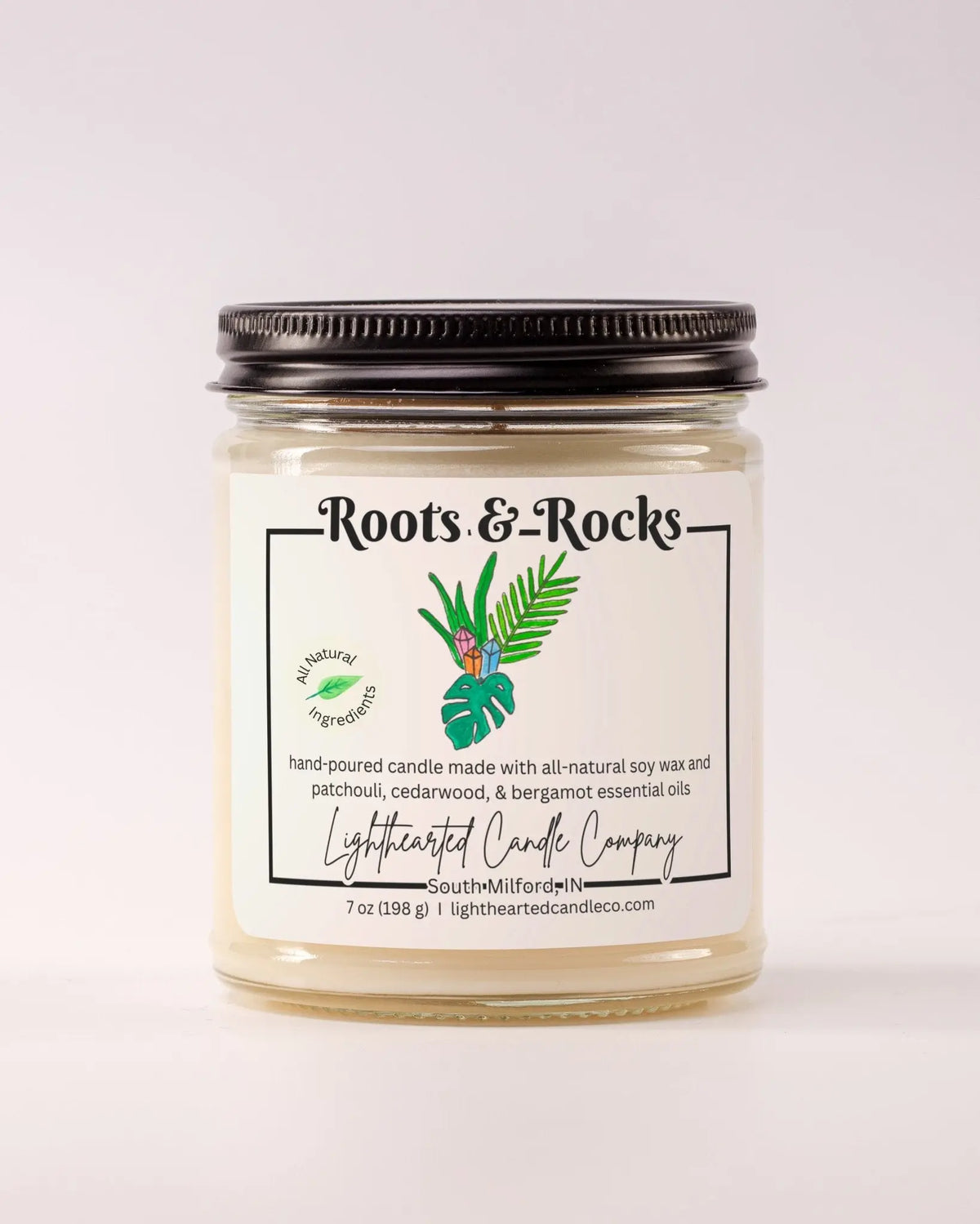 Closed Roots & Rocks Essential Oil Candle in a clear glass jar with a black metal lid