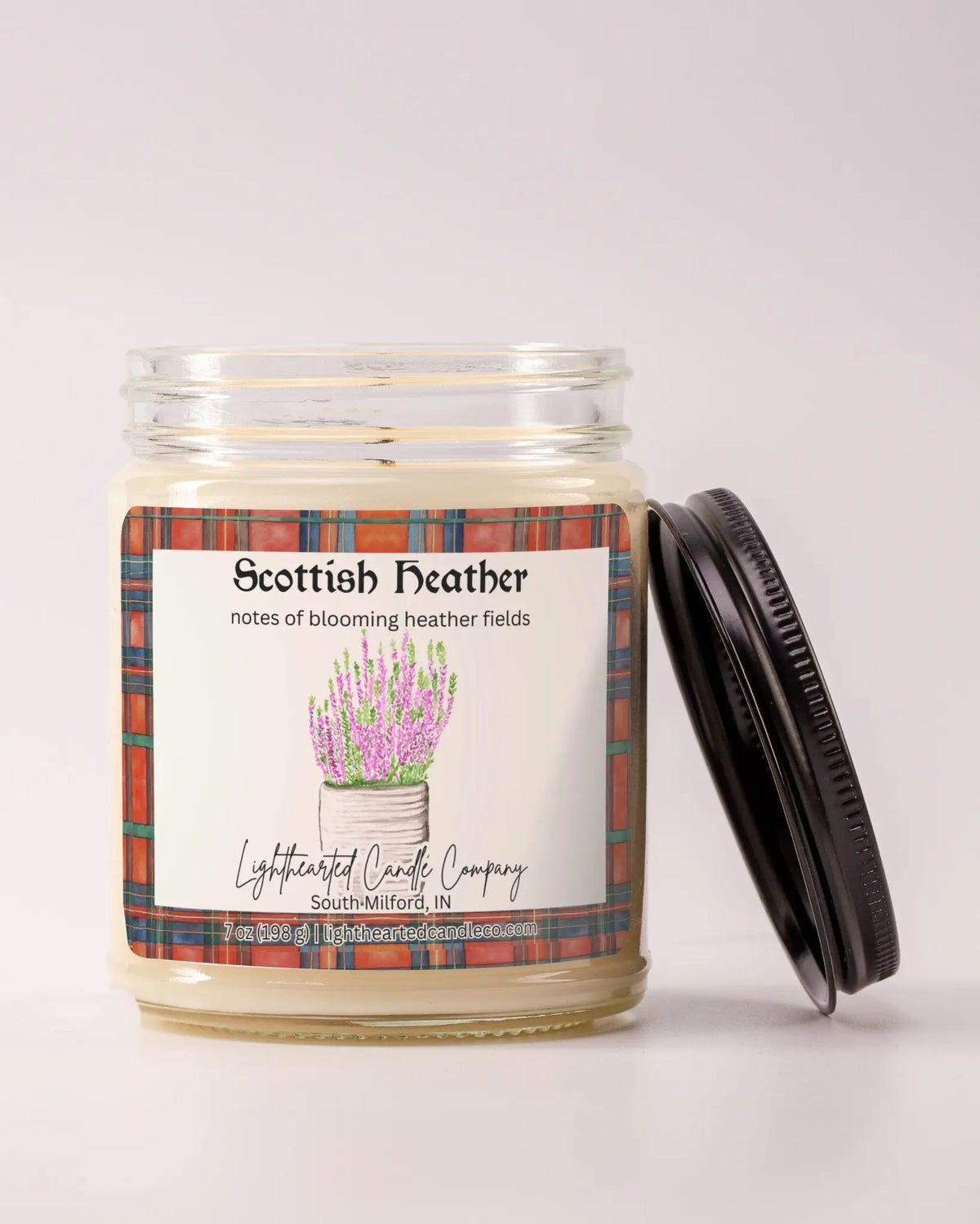 Unlit Scottish Heather Candle in a clear glass jar with its black lid beside it