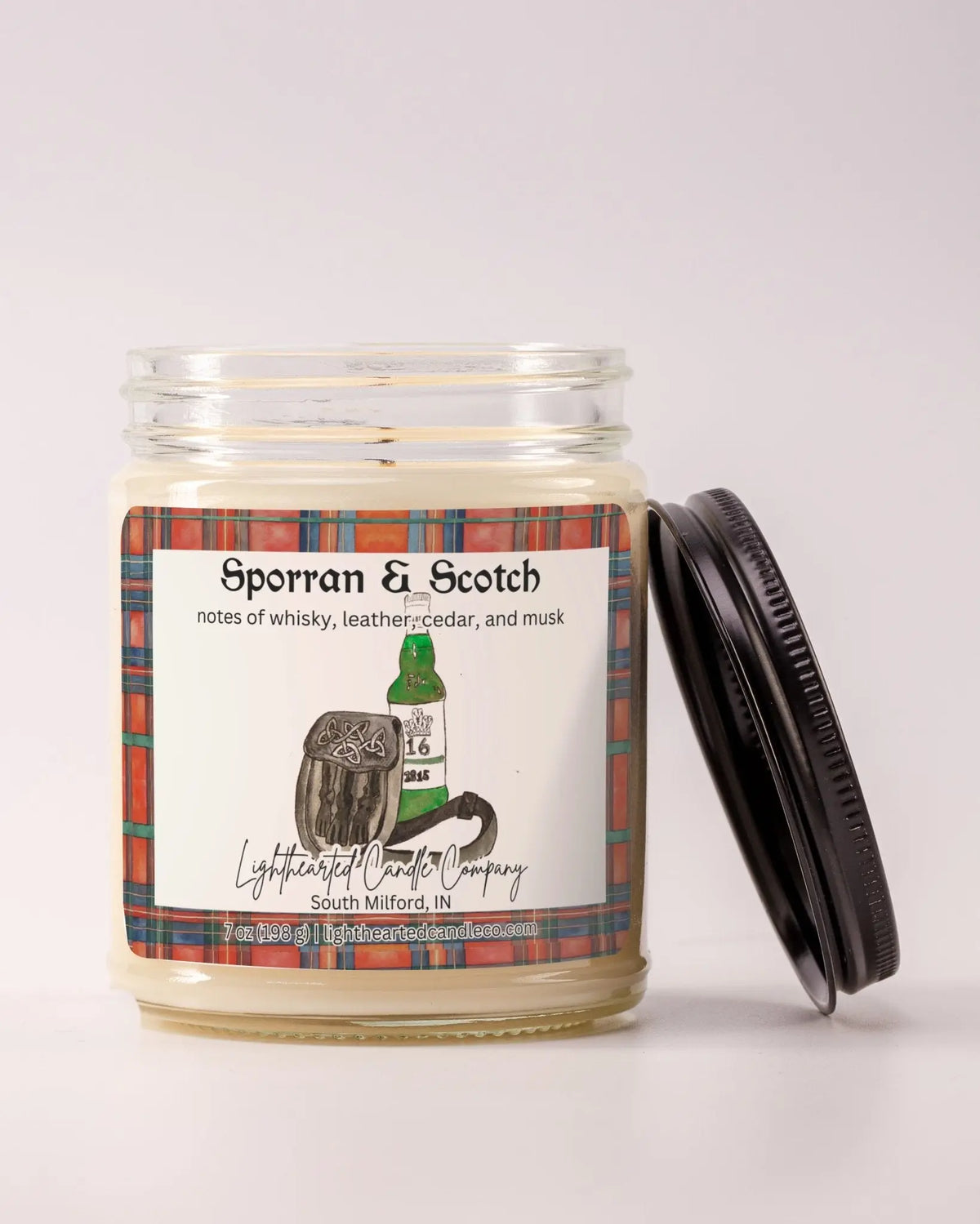 Unlit Sporran & Scotch Candle in a clear glass jar with its black lid beside it