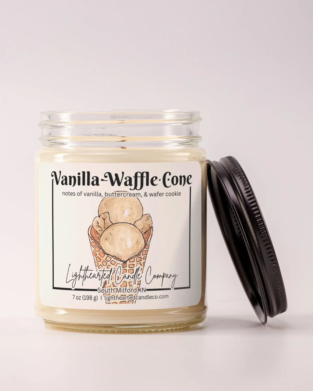 Unlit Vanilla Waffle Cone Candle in a clear glass jar with its black lid beside it