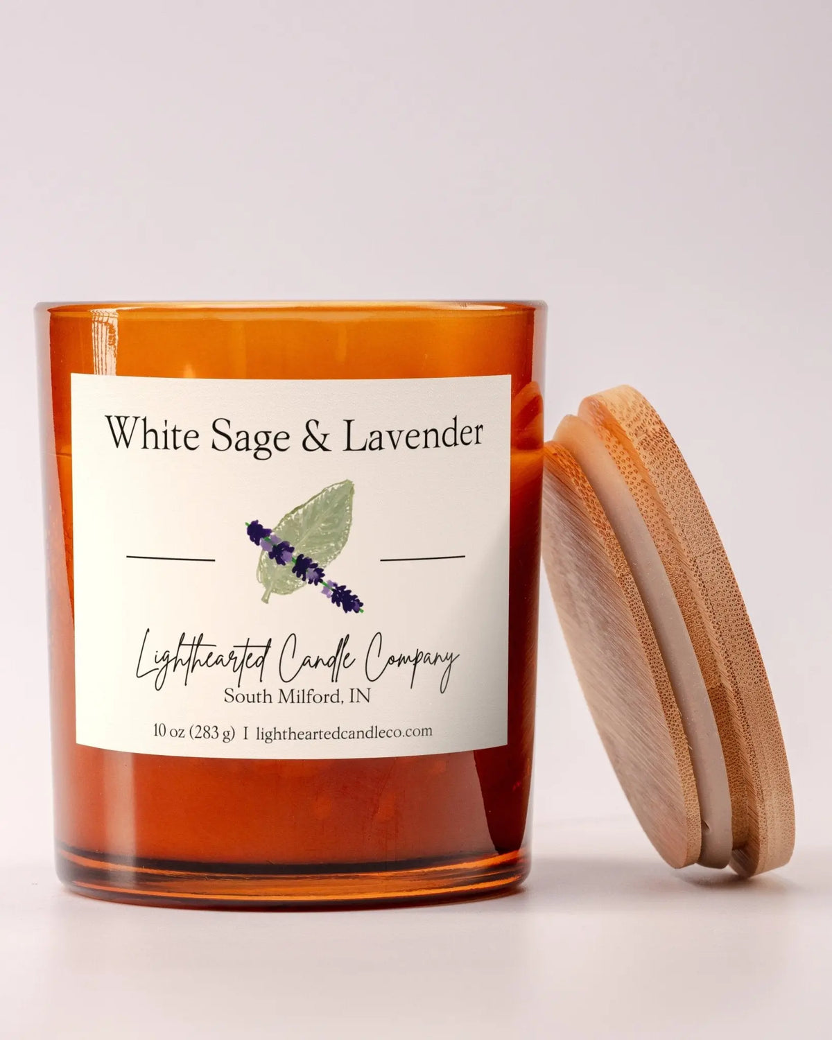 Unlit White Sage & Lavender Candle in an amber glass jar with its wooden lid beside it