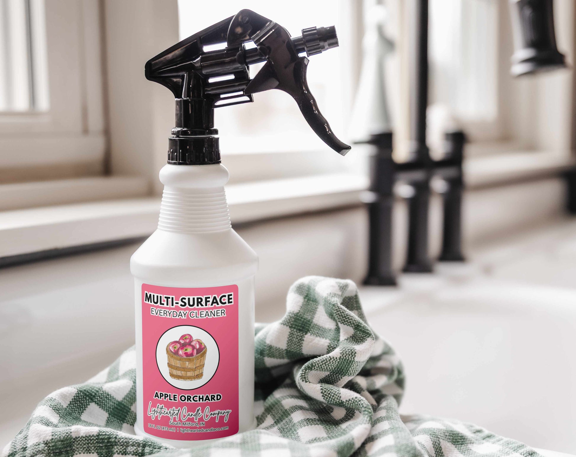 Apple Orchard Cleaning Spray styled on a kitchen counter with a green checkered towel