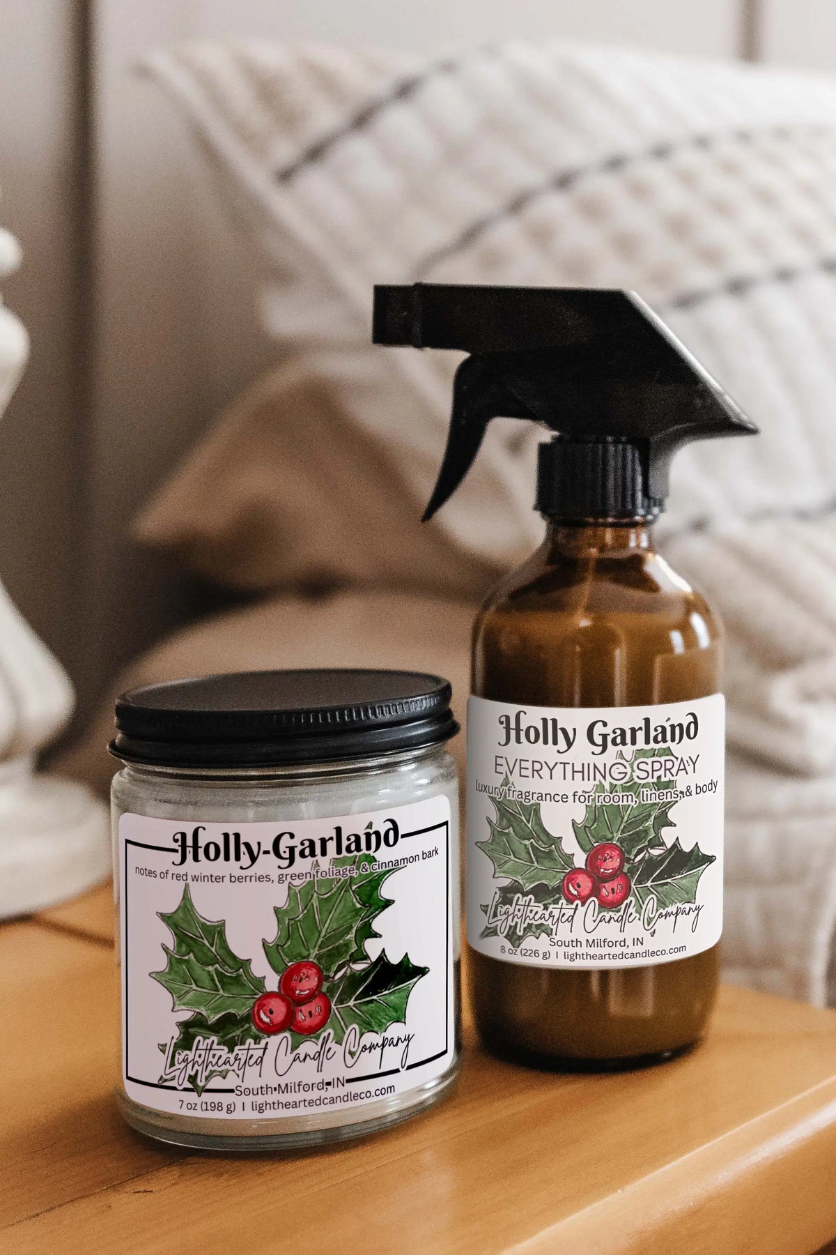 Matching candle and Holly Garland Everything Spray styled on a bedside table