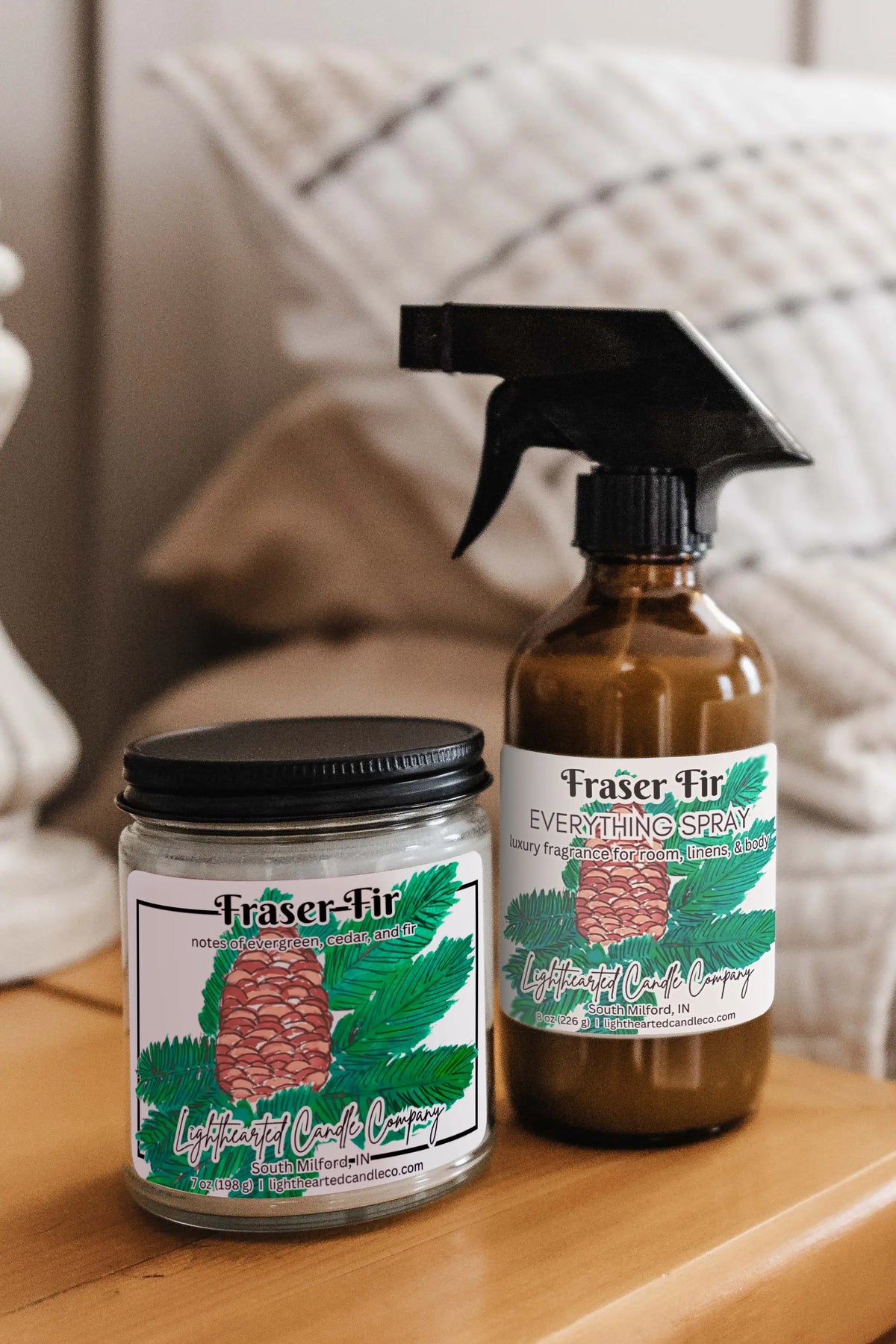 Matching candle and Fraser Fir Everything Spray styled on a bedside table