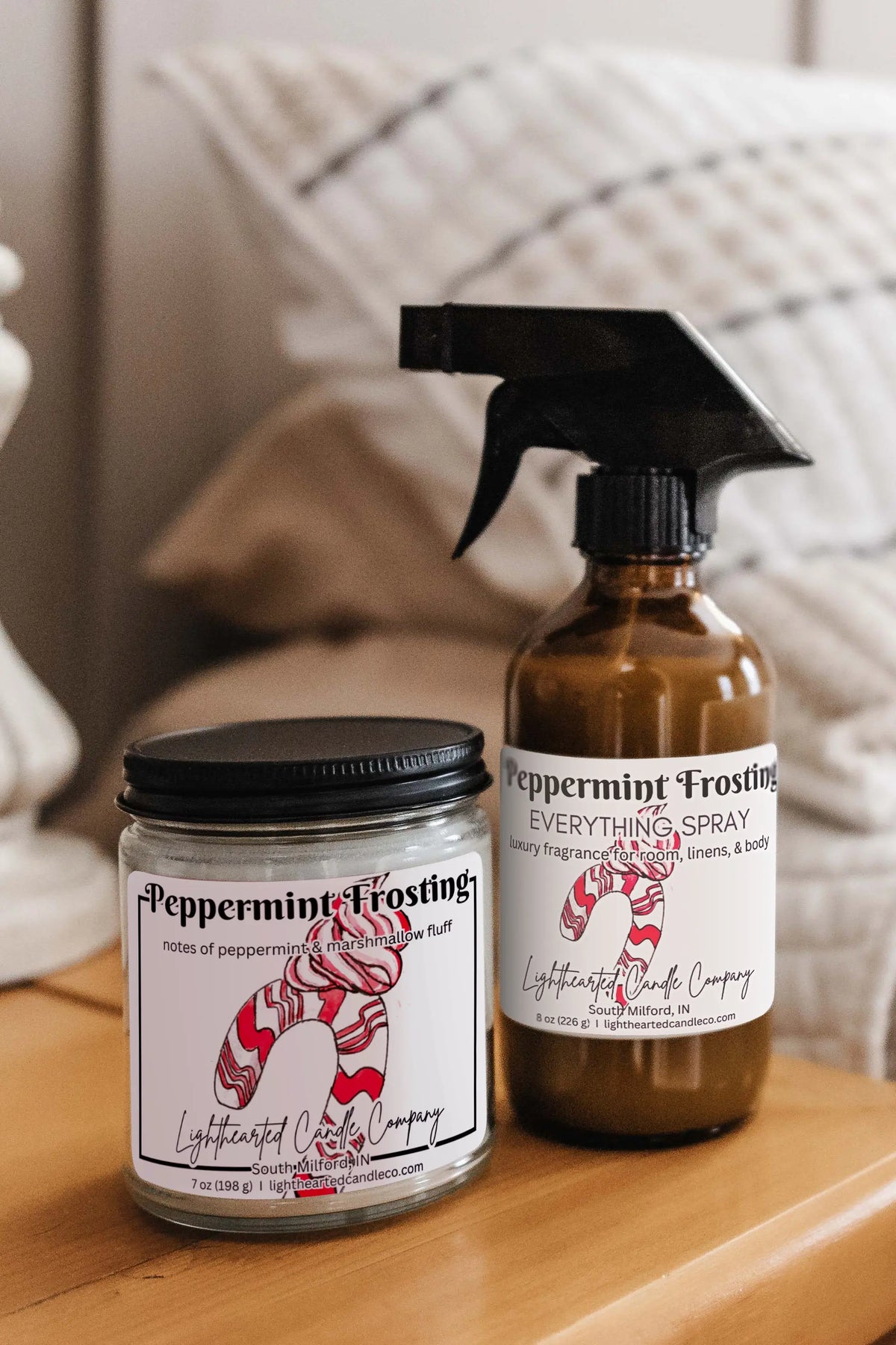Matching candle and Peppermint Frosting Everything Spray styled on a bedside table