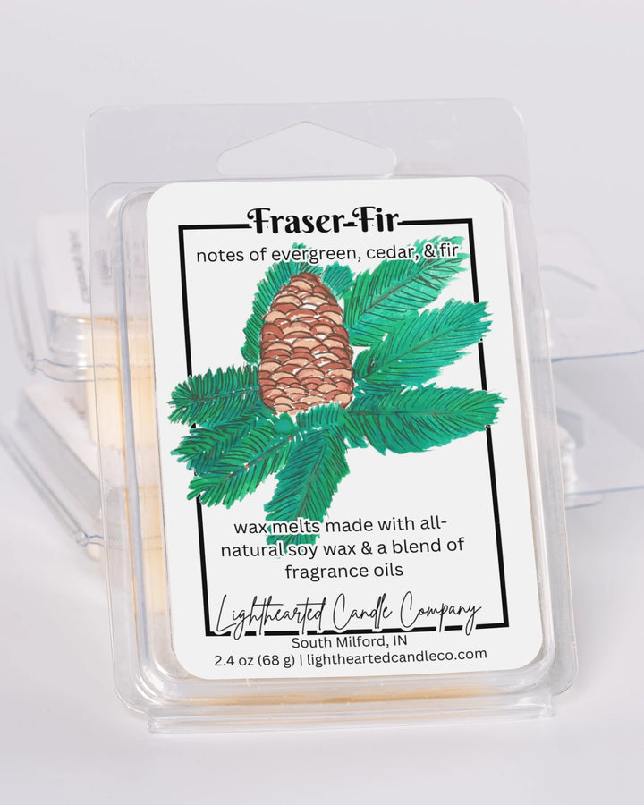 Fraser Fir Wax Melt clamshells stacked at an angle on a pale background