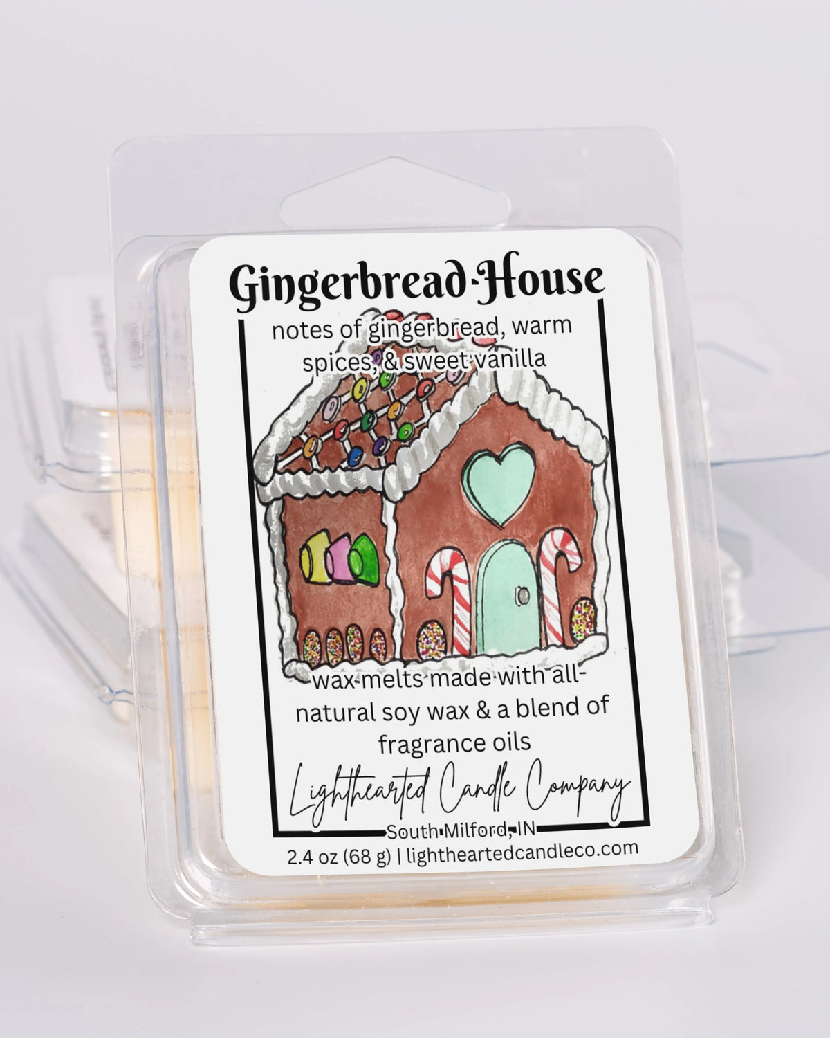 Gingerbread House Wax Melt clamshells stacked at an angle on a pale background