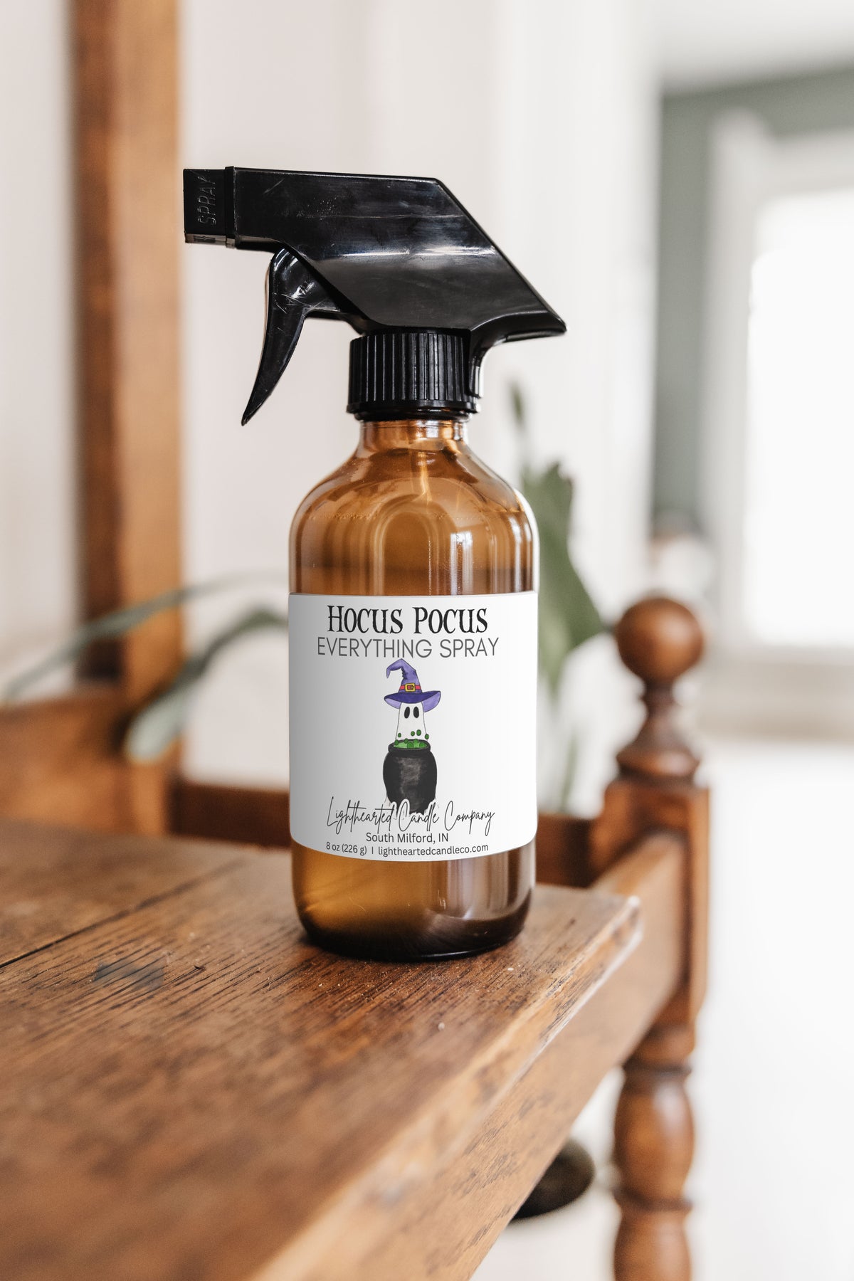 Hocus Pocus Everything Spray in an amber glass bottle in a styled indoor setting