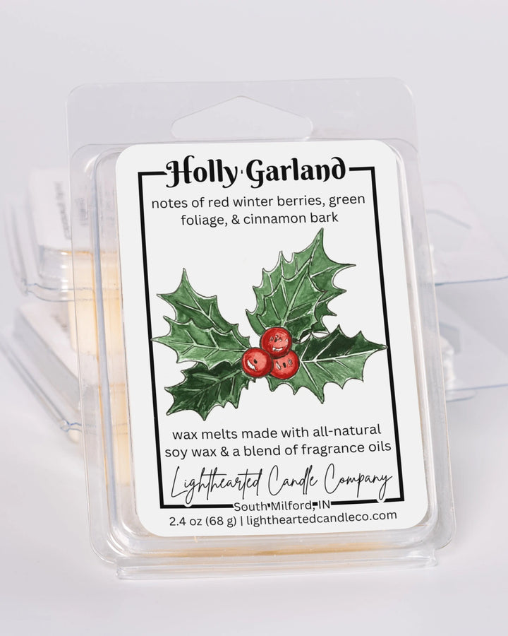 Holly Garland Wax Melt clamshells stacked at an angle on a pale background