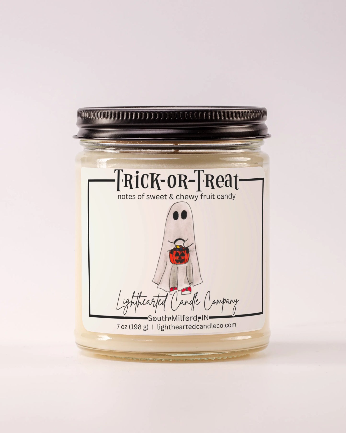 Closed Trick or Treat Candle in a clear glass jar with a black metal lid