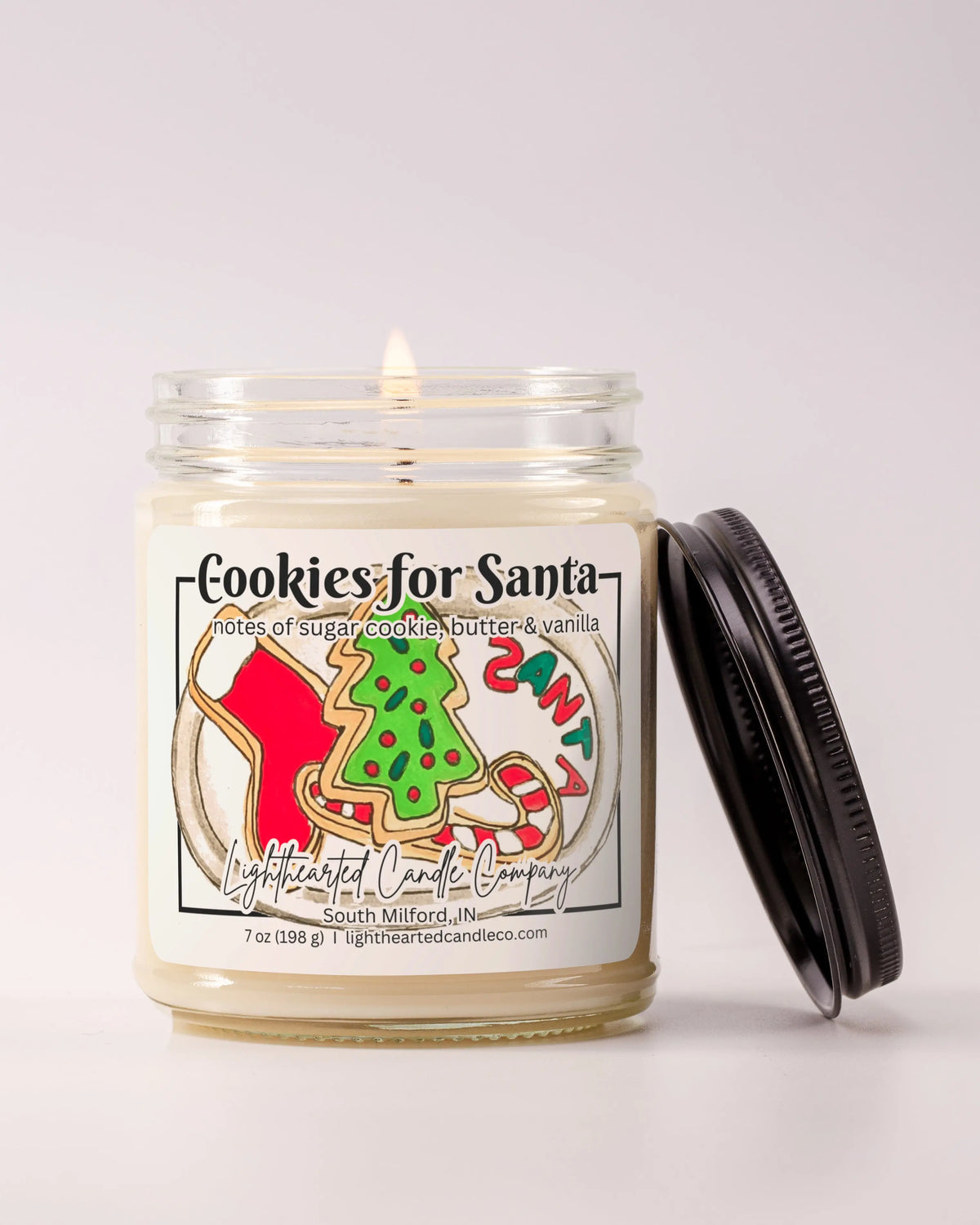 Lit Cookies for Santa Candle in a clear glass jar with its black lid beside it