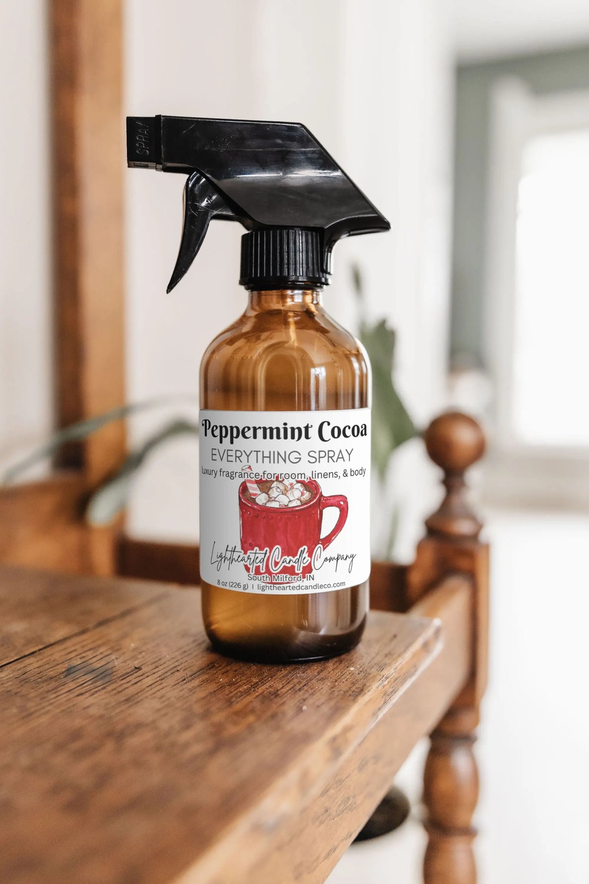Peppermint Cocoa Everything Spray in an amber glass bottle on a wooden dresser