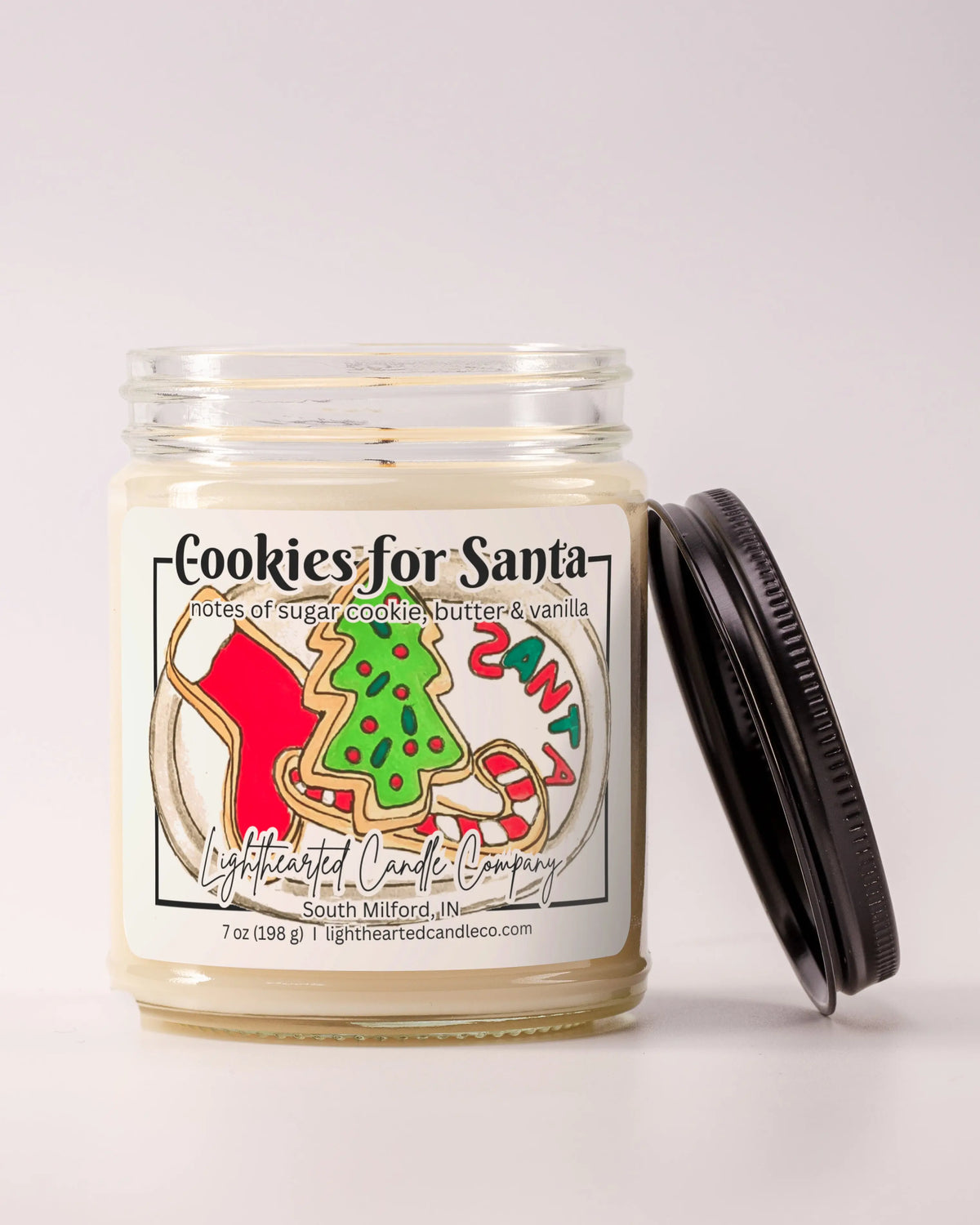 Unlit Cookies for Santa Candle in a clear glass jar with its black lid beside it