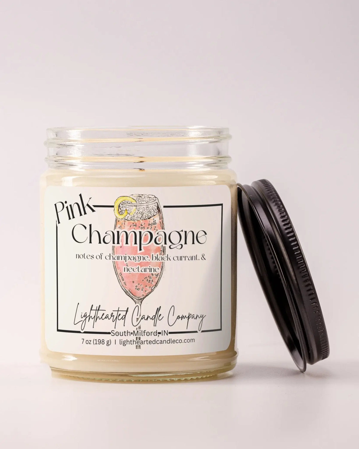Unlit Pink Champagne Candle in a clear glass jar with its black lid beside it