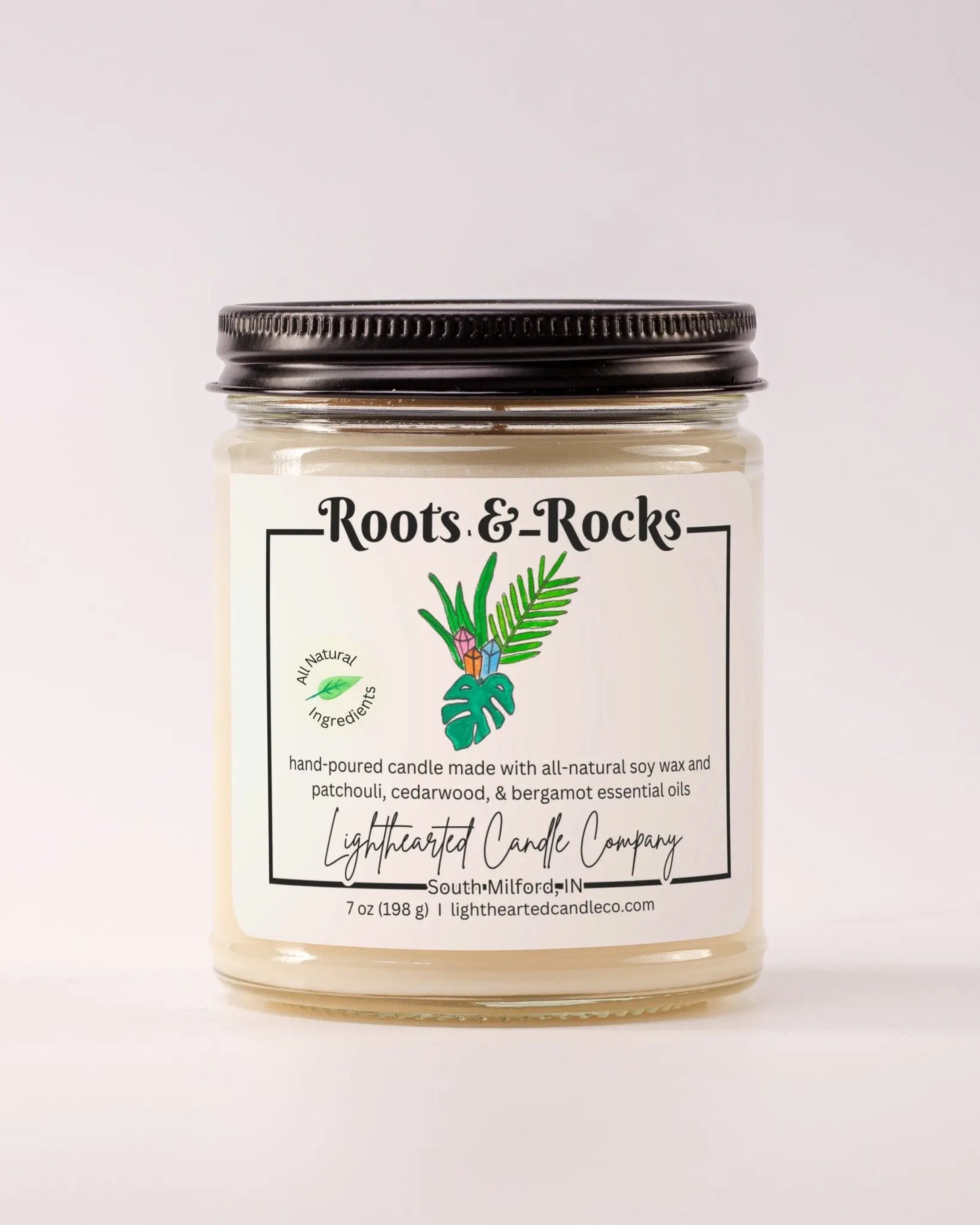 Closed Roots & Rocks Essential Oil Candle in a clear glass jar with a black metal lid